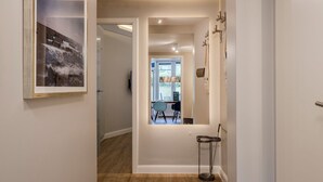 A hallway with a framed picture, a door leading to a room, and a small table with a broom. - Kamperhof, App. 5 - Modern vacation apartment with 3 rooms on approx. 87 m², for max. (Sylt)