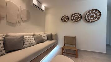 Una sala moderna con un sofá, una silla y tres elementos decorativos colocados en la pared.