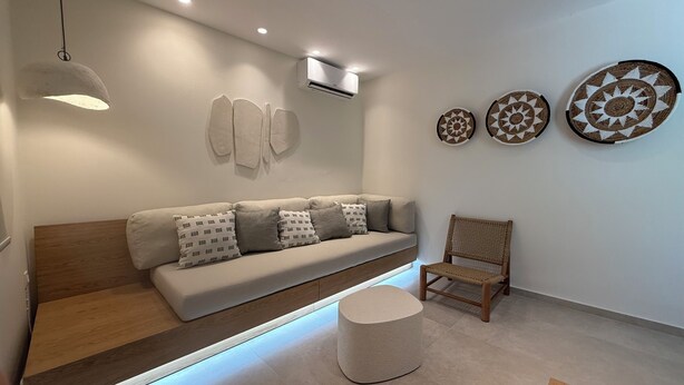 A modern living room with a sofa, a chair, a round ottoman, and wall art. - Family Apartment, Ammos Skiathos (Skiathos)