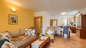 Una sala de estar con sofá, sillas, una mesa de centro y un comedor con mesa y sillas.