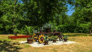 Un jardin avec une charrette en bois, des plantes en pot et un banc.