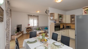 Cocina moderna con refrigerador, microondas y horno. Hay una mesa de comedor para dos personas, con platos y vasos.