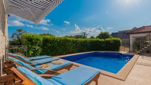 A swimming pool with lounge chairs, a tiled deck, and a stone wall. - Villa Bilanžic - Omiš by Villas Guide (Kreševo)