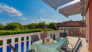 A terrace with a table set for dining, a pool, and a view of greenery and a building in the background. - Villa Bilanžic - Omiš by Villas Guide (Kreševo)