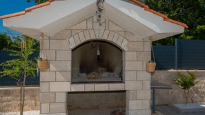 An outdoor brick oven with a white roof and hanging light fixtures.