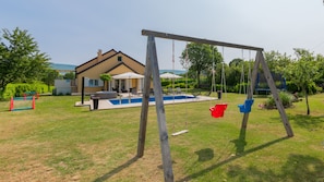 Un jardin avec une balançoire, une piscine et une maison.