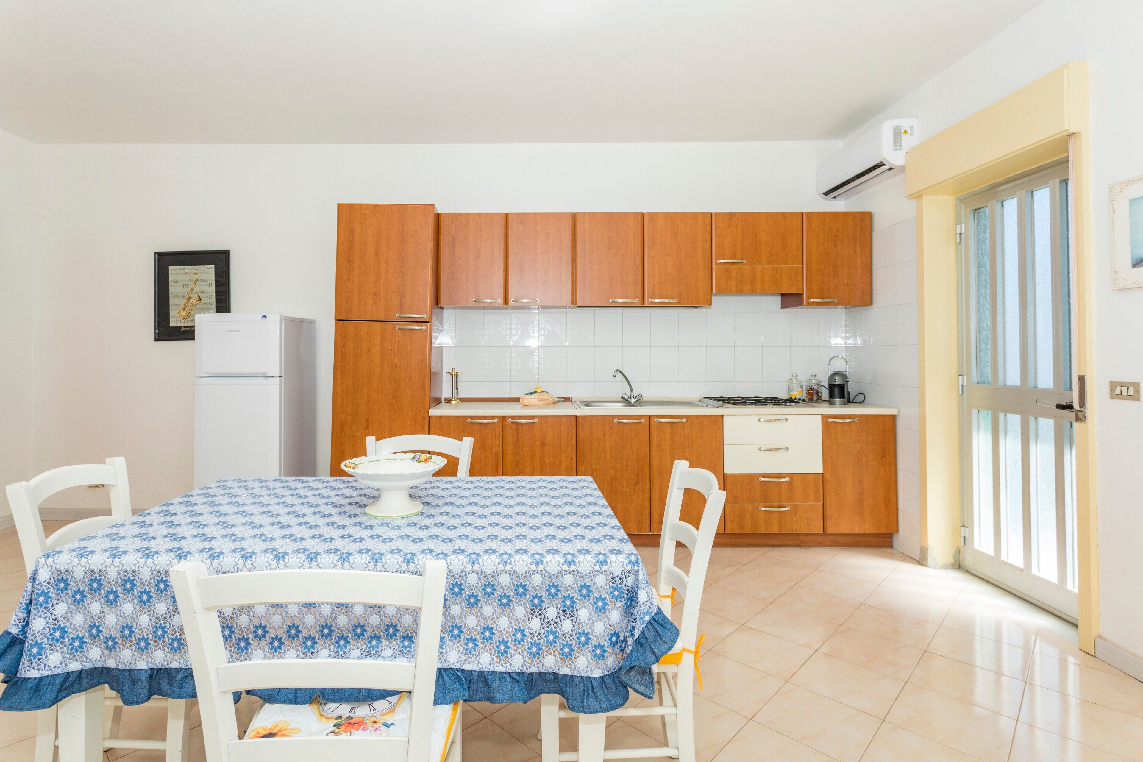 A kitchen with wooden cabinets, a white refrigerator, and a dining table with chairs.