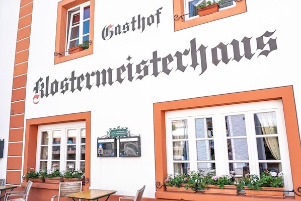 Un bâtiment portant une enseigne indiquant « Gasthof Klostermeisterhaus » et doté d’une terrasse avec des jardinières.