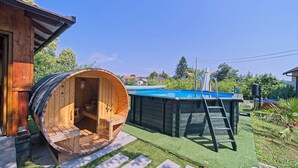 Una sauna de madera con un banco de madera y una pequeña construcción de madera junto a una piscina.
