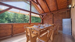 A wooden dining table with chairs, a refrigerator, and a window with a view of trees. - House Kiki by Villas Guide (Bosiljevo)