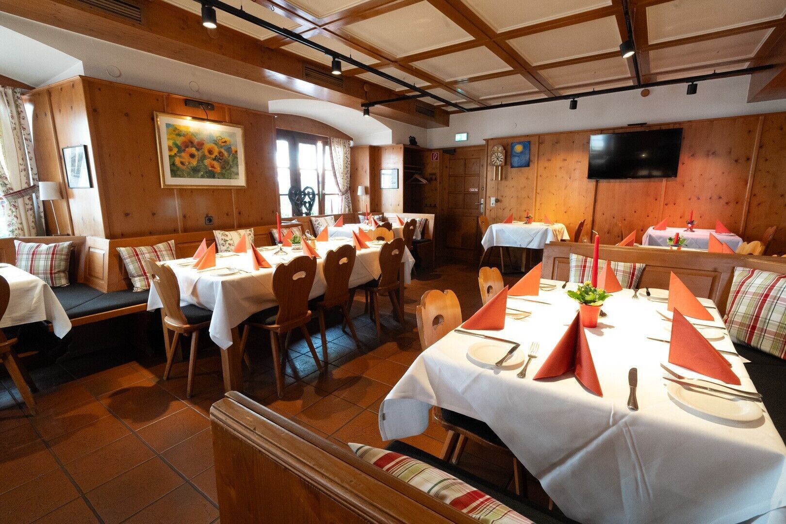 Un restaurante con paredes de paneles de madera, manteles blancos y servilletas anaranjadas.