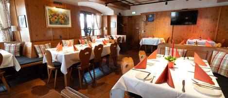 Un restaurante con paredes de paneles de madera, manteles blancos y servilletas anaranjadas.