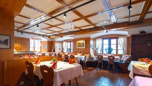 A restaurant with wooden interiors, multiple tables, and chairs.