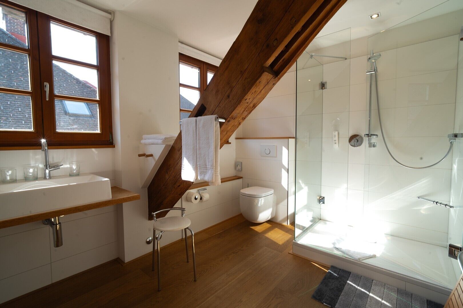 Ein modernes Badezimmer mit Dusche, Toilette, Waschbecken und Holzbalken.
