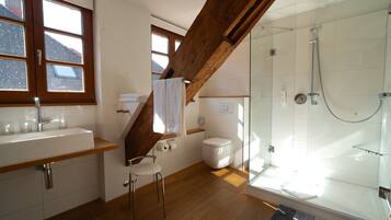Ein modernes Badezimmer mit Dusche, Toilette, Waschbecken und Holzbalken.