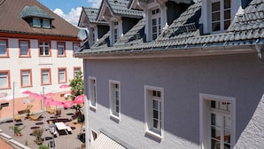 A building with multiple windows and a balcony. There is a small outdoor seating area with tables and chairs. - Room 'Single Room 1' with Shared Garden and Wi-Fi (St Blasien)
