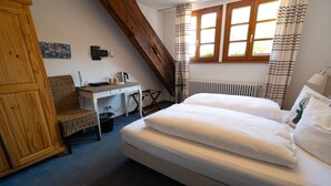 A bedroom with a bed, a desk, a chair, a radiator, and a window with curtains. - Room 'Double Room 8' with Shared Garden and Wi-Fi (St Blasien)