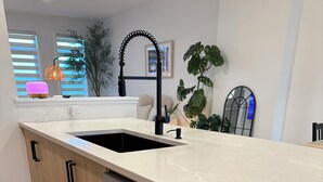 Een moderne keuken met een RVS vaatwasser, een dubbele spoelbak en houten kastjes.