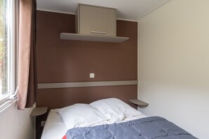 Une chambre à coucher comprenant un lit, une armoire, une table de chevet et une fenêtre avec des rideaux.