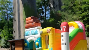 An inflatable play structure with various shapes and colors, including a tall cylindrical tower labeled 'N7' and a smaller play area with a green mat.