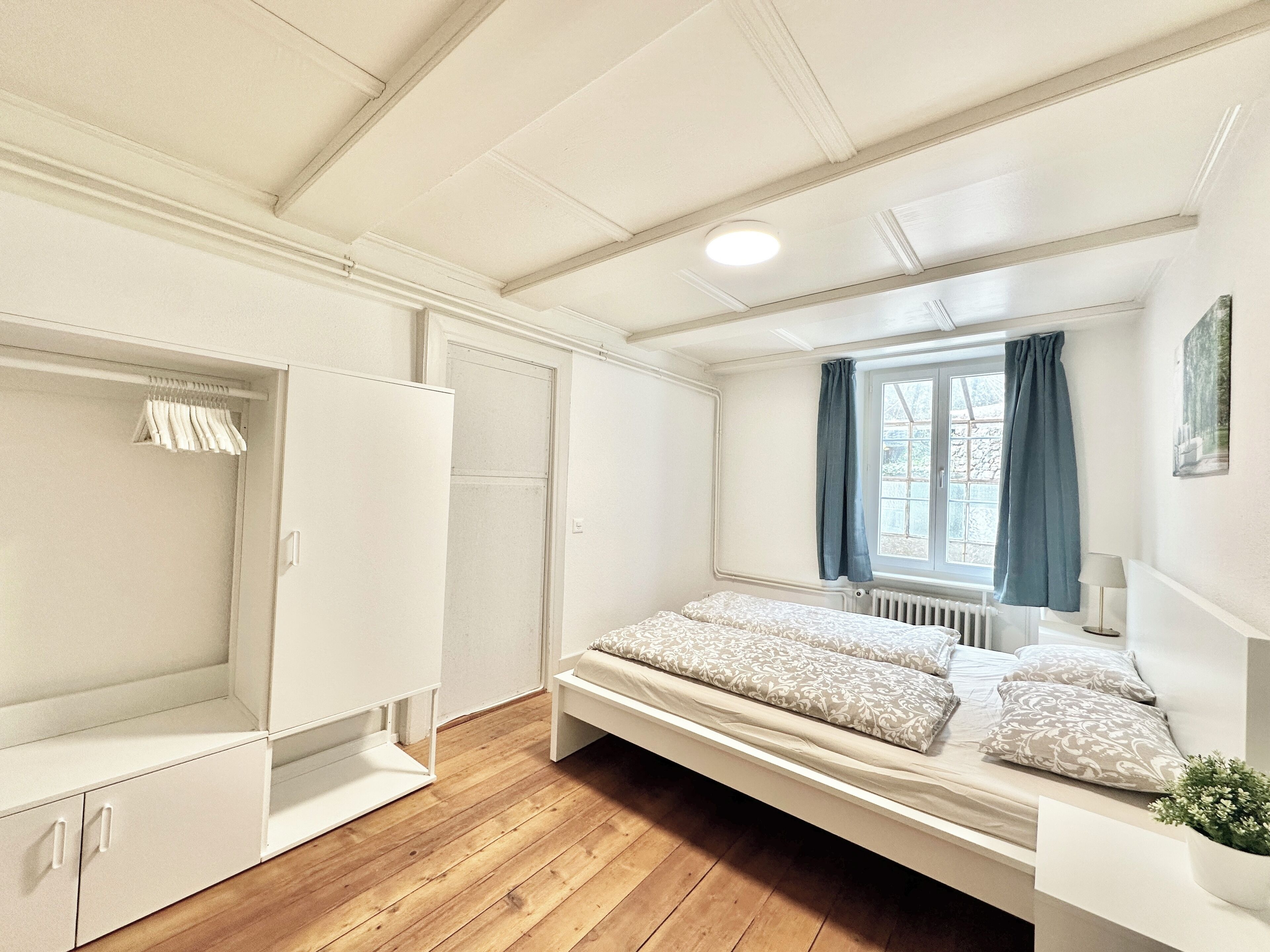 Een slaapkamer met een bed, een kledingkast en een raam met gordijnen.