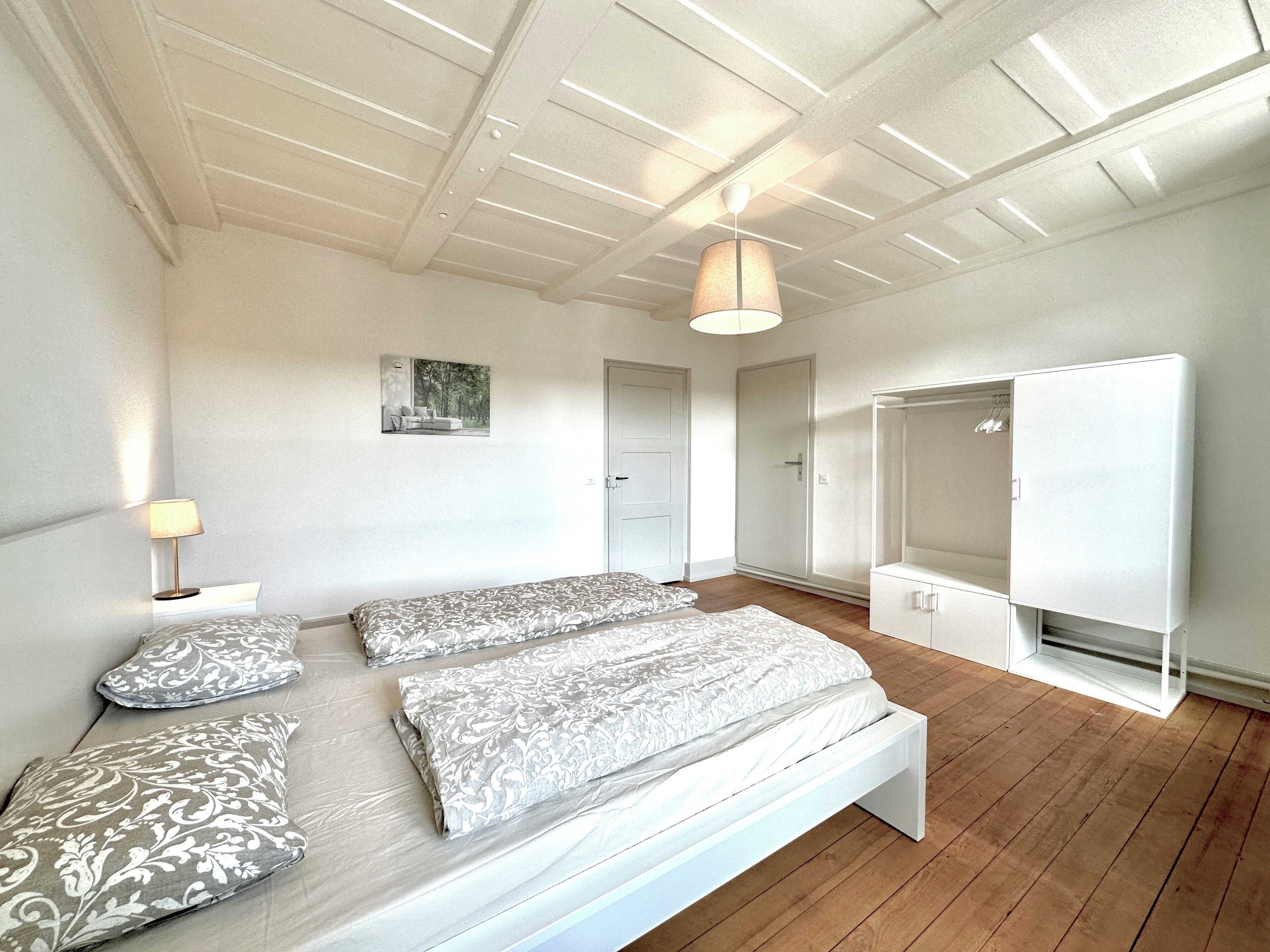 A bedroom with a bed, bedside lamps, a wardrobe, and a ceiling light fixture.