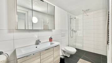 Ein modernes Badezimmer mit Waschbecken, Spiegel und Toilette in Weiß.