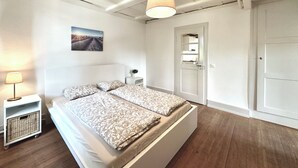 A bedroom with a bed, bedside table, lamp, and a door. - Business Apartment Oberbipp (Oberbipp)