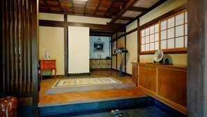 A traditional Japanese interior with tatami flooring, a shoji screen, and a low wooden bench. - 120-years-old house in Kobe with authentic Japanese decor & cultural experiences (Kobe)