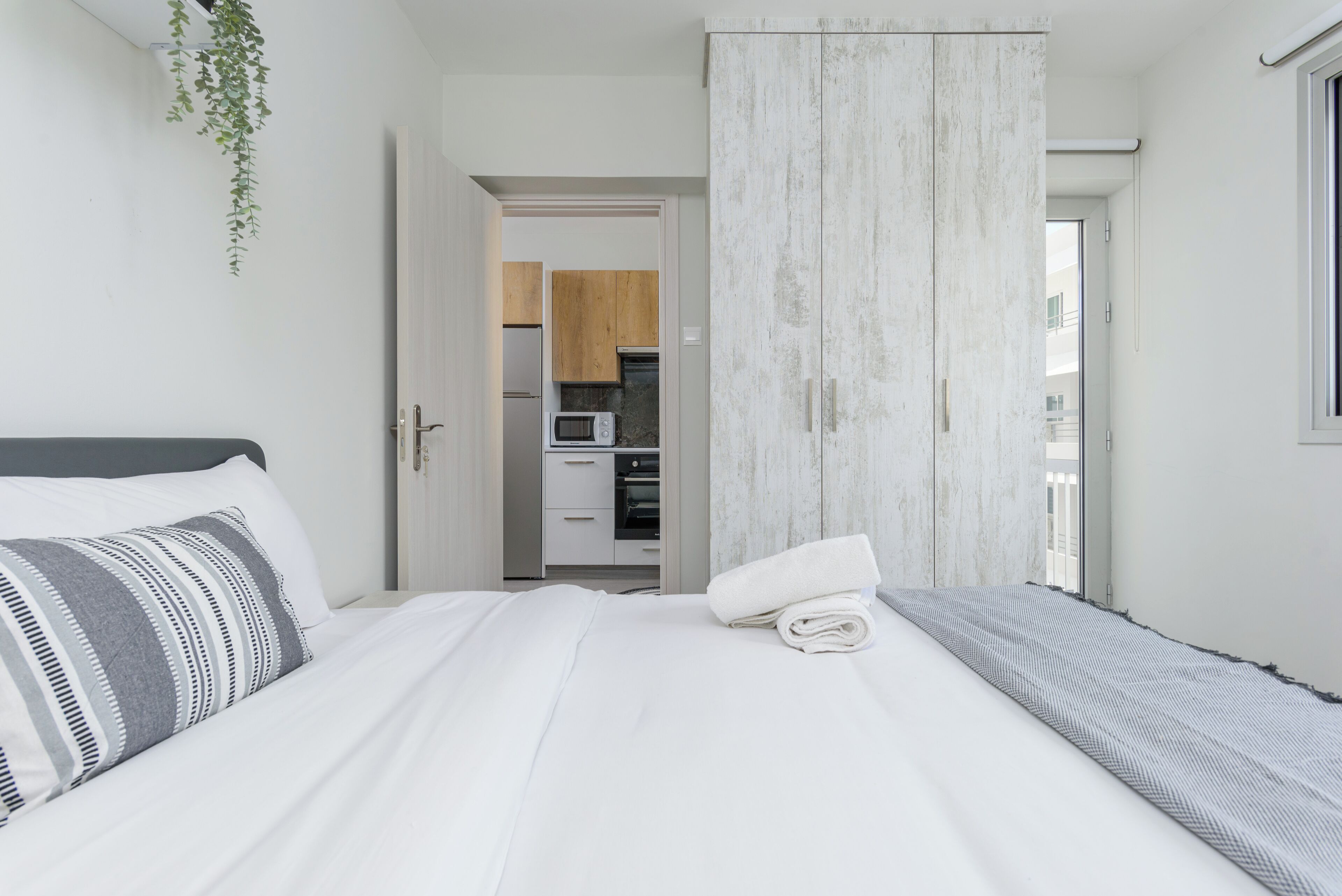 Quarto com cama, guarda-roupa e vista para a cozinha.