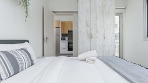 A bedroom with a bed, a wardrobe, and a view into the kitchen. - Amore 2-BR Apt By Finikoudes (Larnaca)