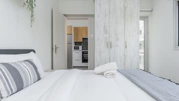 Quarto com cama, guarda-roupa e vista para a cozinha.