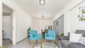 A modern living room with two blue armchairs, a grey sofa, and a glass coffee table. - Amore 2-BR Apt By Finikoudes (Larnaca)