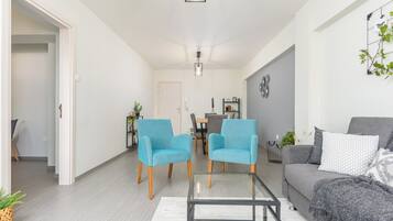 Uma sala de estar moderna com dois poltronas azuis, um sofá cinza e uma mesa de centro de vidro.