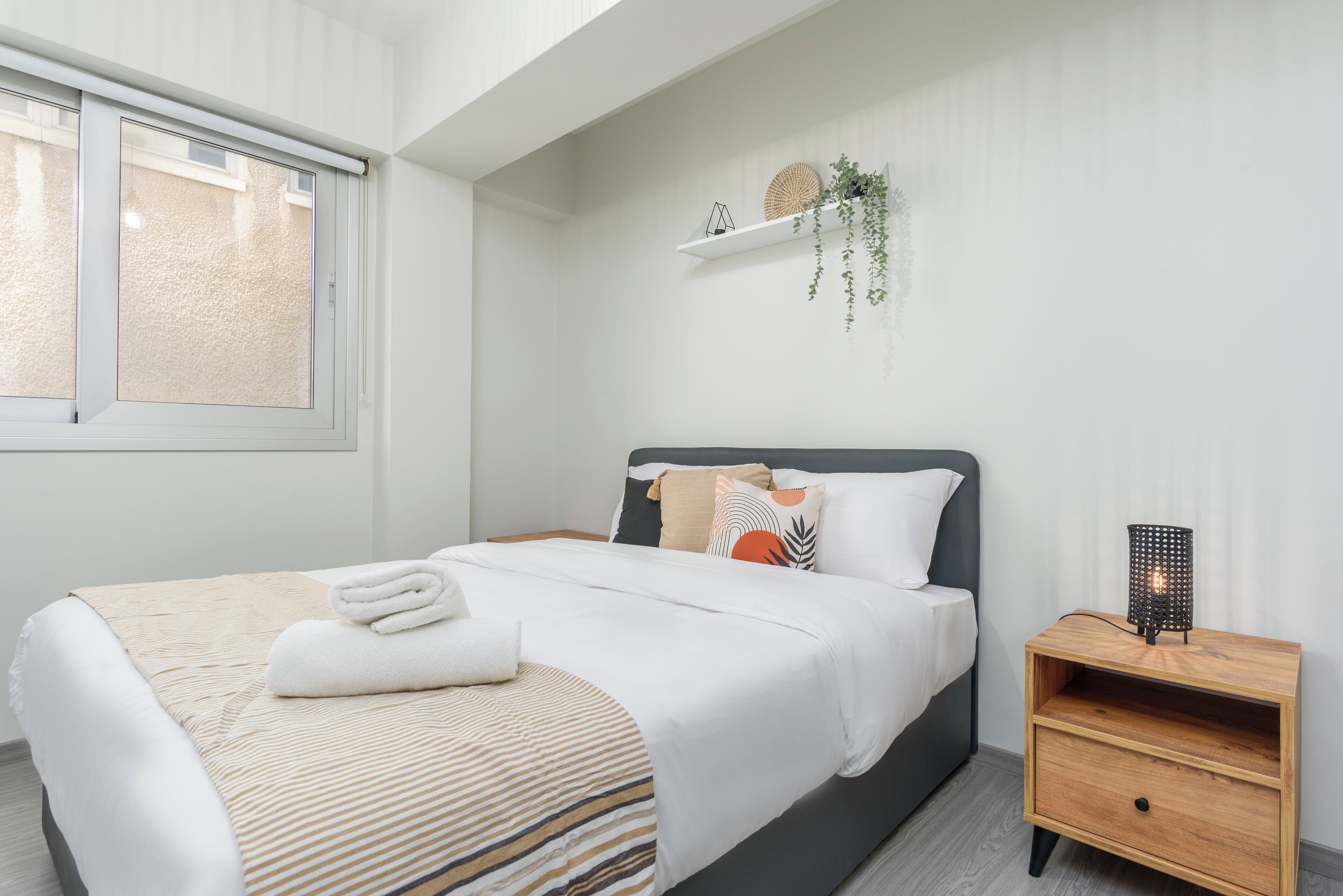 A modern bedroom with a bed, bedside table, and a window.