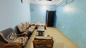 A room with a blue patterned wall, a sofa, a small table, and a door. - Prashi Homes (Varanasi)