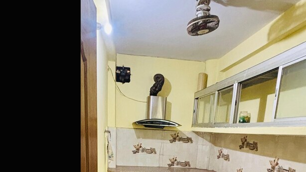 A kitchen with cabinets, a countertop, and a ceiling fan. - Prashi Homes (Varanasi)