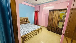 A bedroom with a bed, a wardrobe, and a mirror. - Prashi Homes (Varanasi)
