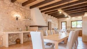 Un comedor rústico con pared de piedra, vigas de madera y suelo de baldosas.