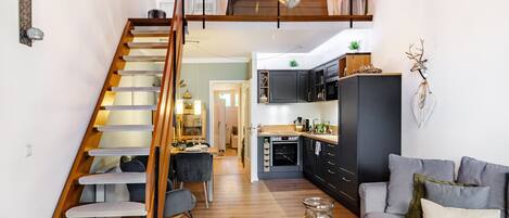 A modern interior with a staircase, kitchen, dining area, and living room.