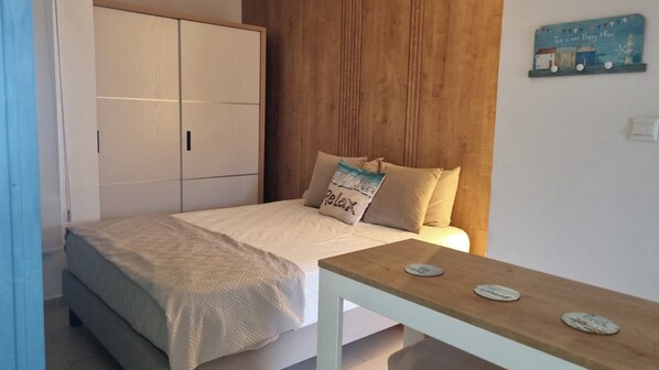 Un dormitorio con cama, cabecera de madera, mesita de noche con adornos y un letrero en la pared.
