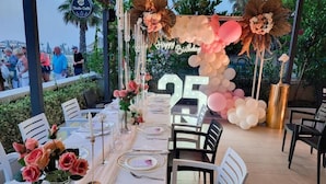 An outdoor dining area with a long table set for a celebration, decorated with flowers and balloons, and a 'Happy Birthday' sign. - Okej Hotel (Golem)