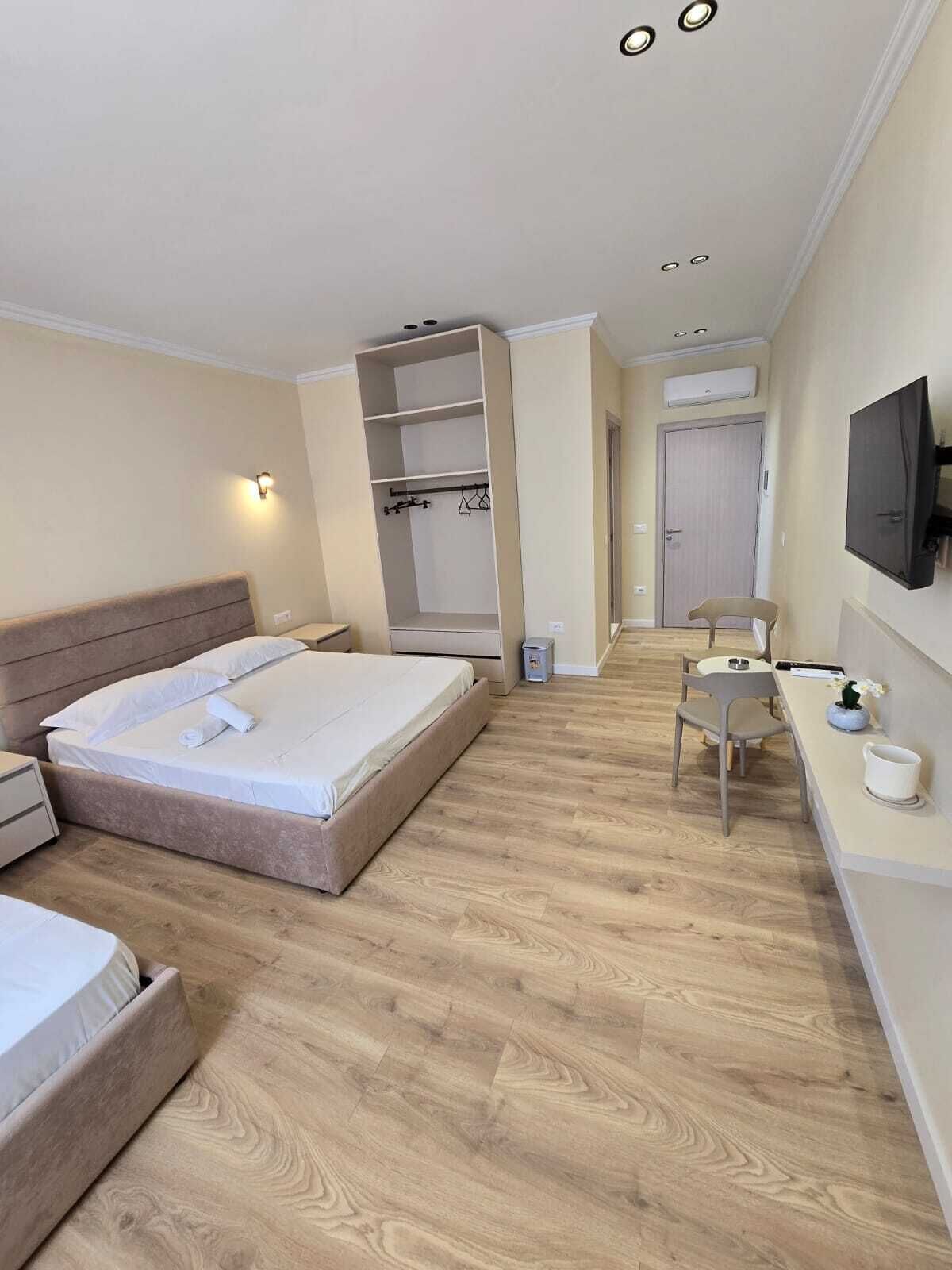 A hotel room with a bed, a desk, a chair, a TV, and a wardrobe.