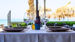 A table set for dining with a view of the ocean, a bottle of wine, and a small vase with flowers. - Okej Hotel (Golem)