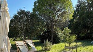 A wooden deck with lounge chairs and a table, surrounded by trees and greenery. - Large family home with swimming pool and air conditioning, suitable for children. (Viols-le-Fort)