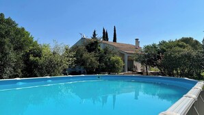 A clear blue swimming pool with a house in the background surrounded by trees. - Large family home with swimming pool and air conditioning, suitable for children. (Viols-le-Fort)