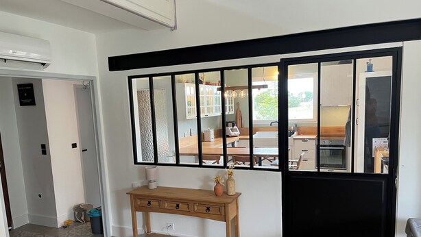 A room with a wooden console table, a black sliding door, and a view of a kitchen through the door. - Large family home with swimming pool and air conditioning, suitable for children. (Viols-le-Fort)