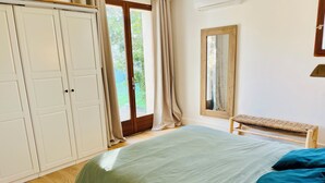 A bedroom with a bed, a bench, a wardrobe, and a window with curtains. - Large family home with swimming pool and air conditioning, suitable for children. (Viols-le-Fort)