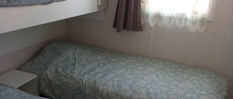 A bunk bed room with a lower bunk and a single bed, both with floral-patterned bedding.