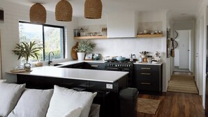 Une cuisine moderne dotée d’un îlot central, de meubles noirs et d’une fenêtre donnant sur un espace verdoyant.